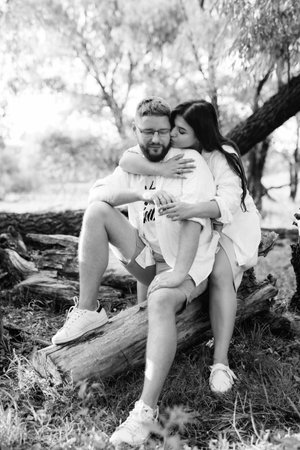 young couple in love a guy with a beard and a girl with dark hair in light clothes in the green forestの写真素材