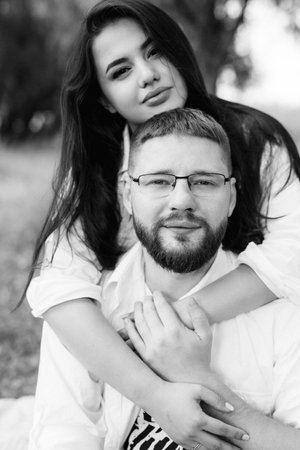 young couple in love a guy with a beard and a girl with dark hair in light clothes in the green forestの写真素材