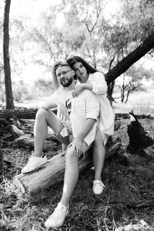 young couple in love a guy with a beard and a girl with dark hair in light clothes in the green forestの写真素材