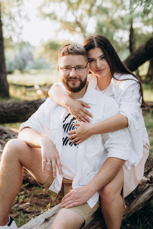 young couple in love a guy with a beard and a girl with dark hair in light clothes in the green forestの写真素材