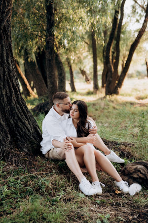 young couple in love a guy with a beard and a girl with dark hair in light clothes in the green forestの写真素材