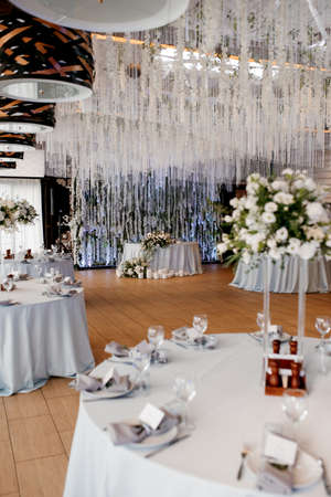 The presidium of the newlyweds in the banquet hall of the restaurant is decorated with candles and green plants, wisteria hangs from the ceilingの写真素材