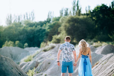 blonde girl in a light blue dress and a guy in a light shirt and short shert in a granite quarry