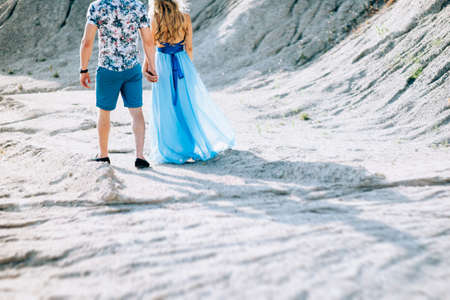blonde girl in a light blue dress and a guy in a light shirt and short shert in a granite quarry