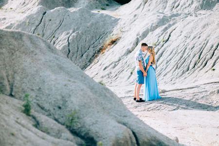 blonde girl in a light blue dress and a guy in a light shirt and short shert in a granite quarryの写真素材
