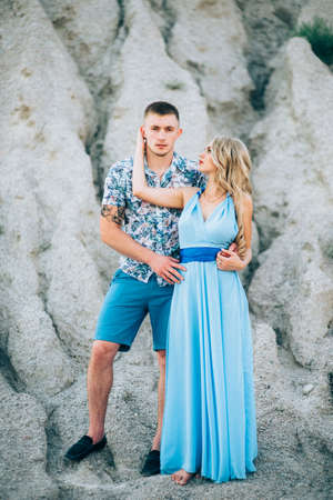 blonde girl in a light blue dress and a guy in a light shirt and short shert in a granite quarryの写真素材
