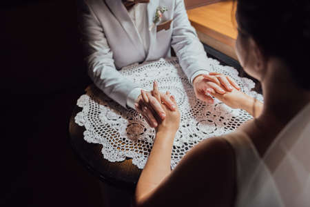 guy in a suit and a girl in a dress are sitting at the table and holding hands and looking into each other's eyesの写真素材