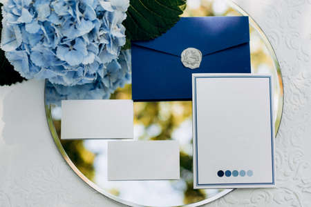 wedding invitation in a gray envelope on a table with green sprigsの写真素材