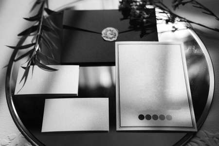 wedding invitation in a gray envelope on a table with green sprigsの写真素材