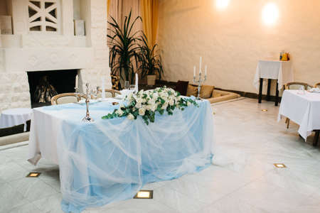 The presidium of the newlyweds in the banquet hall of the restaurant is decorated with candles and green plants, wisteria hangs from the ceilingの写真素材