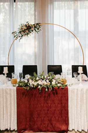 The presidium of the newlyweds in the banquet hall of the restaurant is decorated with candles and green plants, wisteria hangs from the ceilingの写真素材