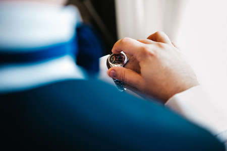the groom in a blue suit looks at the watch worn on his left handの写真素材