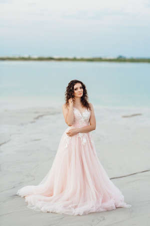 girl in a pink dress are walking along the white sand of the desertの写真素材