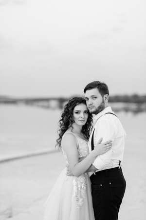 young couple a guy in black breeches and a girl in a pink dress are walking along the white sand of the desertの写真素材