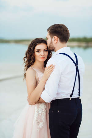 young couple a guy in black breeches and a girl in a pink dress are walking along the white sand of the desertの写真素材