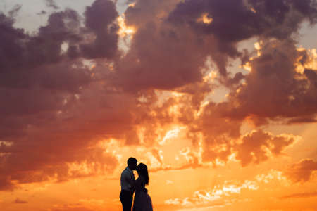 young couple a guy in black breeches and a girl in a pink dress are walking along the white sand of the desertの写真素材