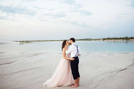 young couple a guy in black breeches and a girl in a pink dress are walking along the white sand of the desertの写真素材
