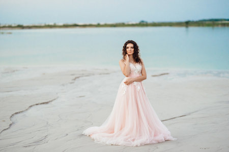 girl in a pink dress are walking along the white sand of the desertの写真素材
