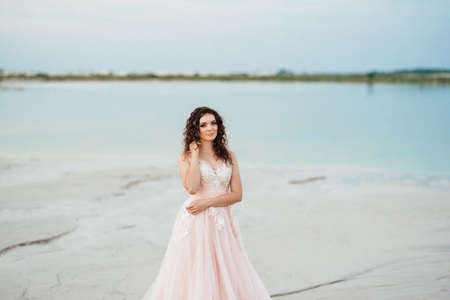 girl in a pink dress are walking along the white sand of the desertの写真素材
