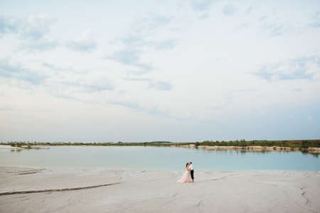 young couple a guy in black breeches and a girl in a pink dress are walking along the white sand of the desertの写真素材