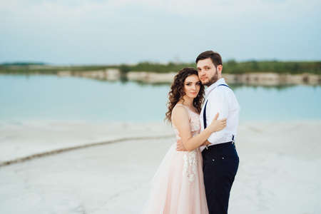 young couple a guy in black breeches and a girl in a pink dress are walking along the white sand of the desertの写真素材