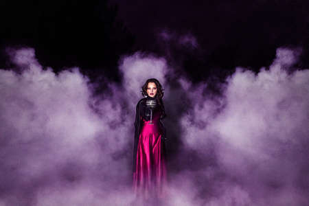 girl alone at night in the forest brews a potion and wonders for marriage, surrounded by candles and smokeの写真素材