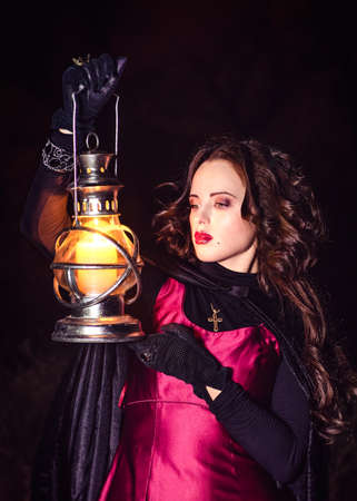 girl alone at night in the forest brews a potion and wonders for marriage, surrounded by candles and smokeの写真素材