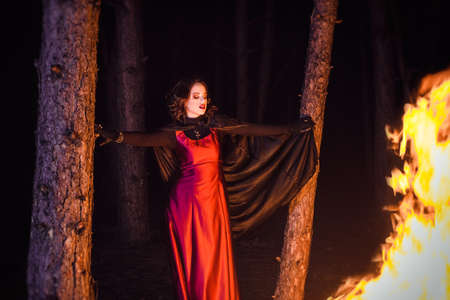 girl alone at night in the forest brews a potion and wonders for marriage, surrounded by candles and smokeの写真素材