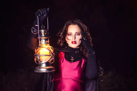 girl alone at night in the forest brews a potion and wonders for marriage, surrounded by candles and smokeの写真素材