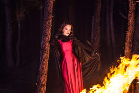girl alone at night in the forest brews a potion and wonders for marriage, surrounded by candles and smokeの写真素材