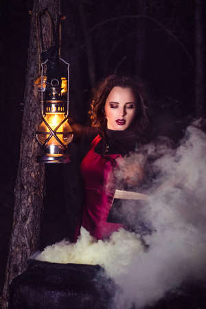 girl alone at night in the forest brews a potion and wonders for marriage, surrounded by candles and smokeの写真素材