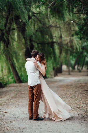 a guy and a girl are walking along the banks of a wild river overgrown with willows and forestの写真素材