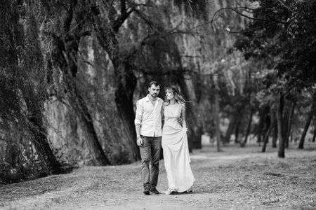 a guy and a girl are walking along the banks of a wild river overgrown with willows and forestの写真素材