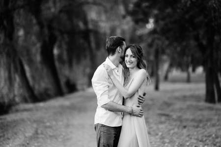 a guy and a girl are walking along the banks of a wild river overgrown with willows and forestの写真素材
