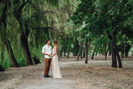 a guy and a girl are walking along the banks of a wild river overgrown with willows and forestの写真素材