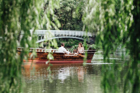 a boat trip for a guy and a girl along the canals and bays of the river overgrown with wild willowsの写真素材