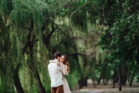 a guy and a girl are walking along the banks of a wild river overgrown with willows and forestの写真素材