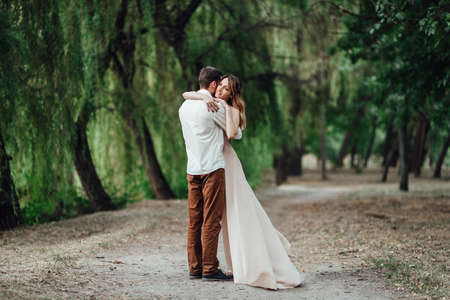 a guy and a girl are walking along the banks of a wild river overgrown with willows and forestの写真素材