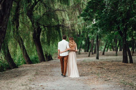 a guy and a girl are walking along the banks of a wild river overgrown with willows and forestの写真素材