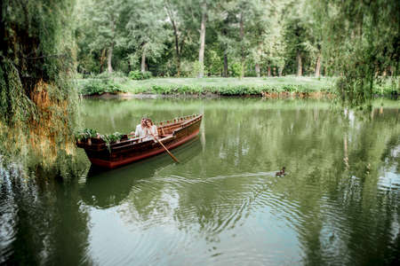 a boat trip for a guy and a girl along the canals and bays of the river overgrown with wild willowsの写真素材