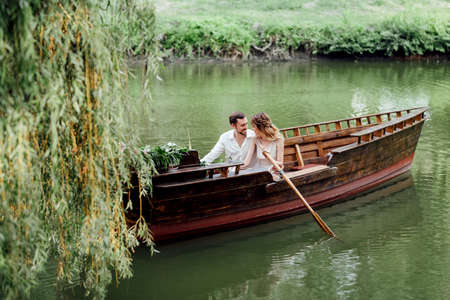 a boat trip for a guy and a girl along the canals and bays of the river overgrown with wild willowsの写真素材