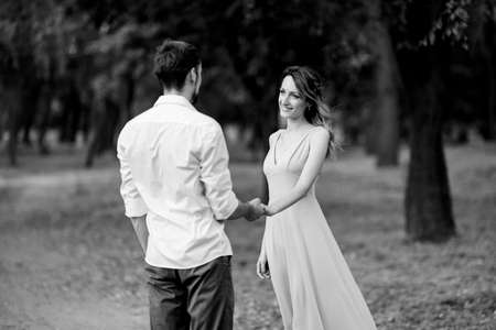 a guy and a girl are walking along the banks of a wild river overgrown with willows and forestの写真素材