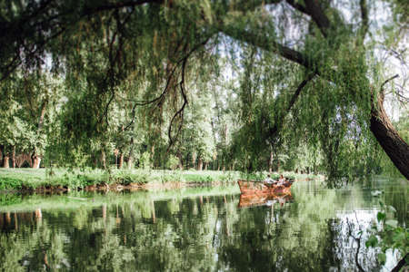 a boat trip for a guy and a girl along the canals and bays of the river overgrown with wild willowsの写真素材
