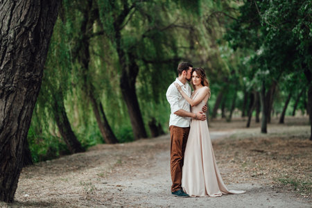 a guy and a girl are walking along the banks of a wild river overgrown with willows and forestの写真素材