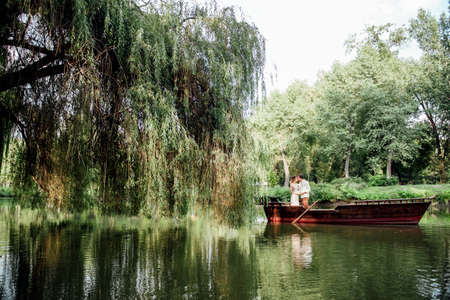 a boat trip for a guy and a girl along the canals and bays of the river overgrown with wild willowsの写真素材