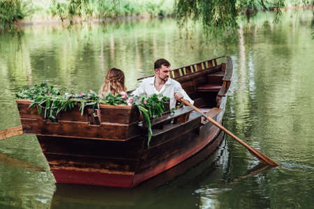 a boat trip for a guy and a girl along the canals and bays of the river overgrown with wild willowsの写真素材