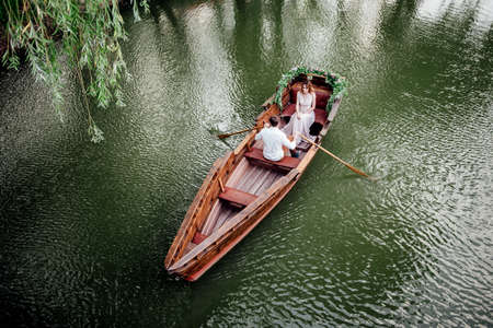 a boat trip for a guy and a girl along the canals and bays of the river overgrown with wild willowsの写真素材