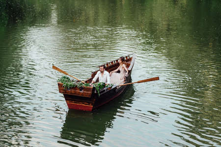 a boat trip for a guy and a girl along the canals and bays of the river overgrown with wild willowsの写真素材