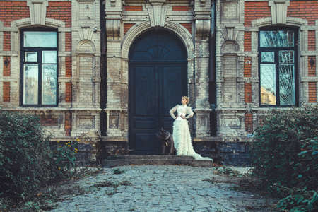 Girl in an old dress with ruffles and a big dark dogの写真素材