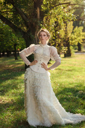 Girl model with white hair in a retro dress with ruffles in a green parkの写真素材
